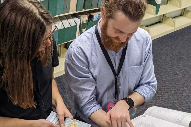 Two researchers looking at books and papers together